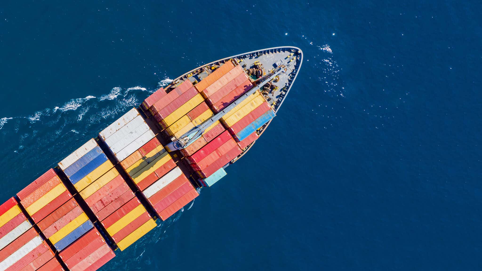 cargo ship full loaded with containers, blue sea background, top